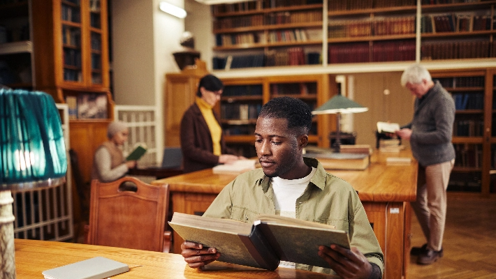 Hombre leyendo libro en biblioteca